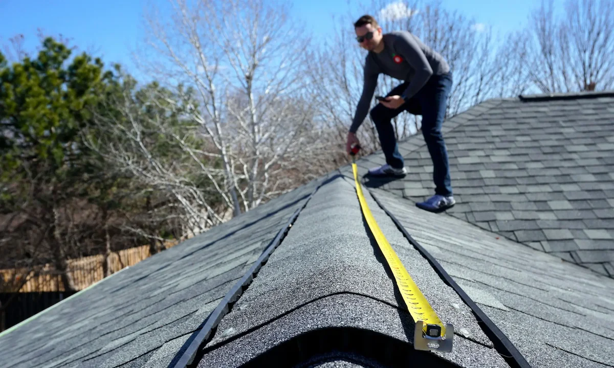 Roofing inspector examining shingles on a DFW home after a hail storm